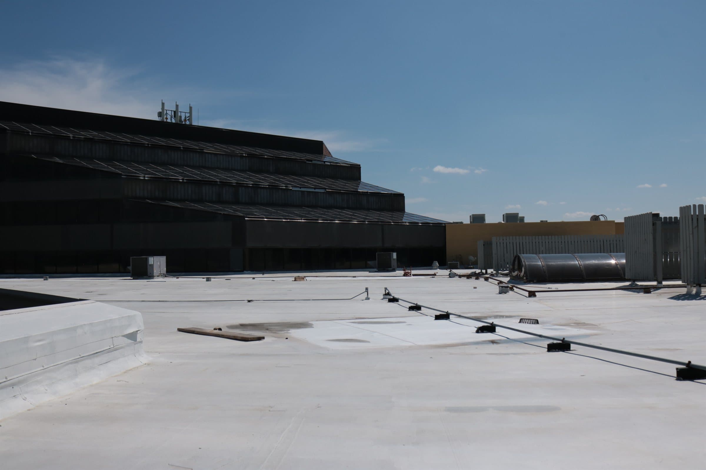 A low-slope commercial roof surface with parapet, roof-top equipment and drainage