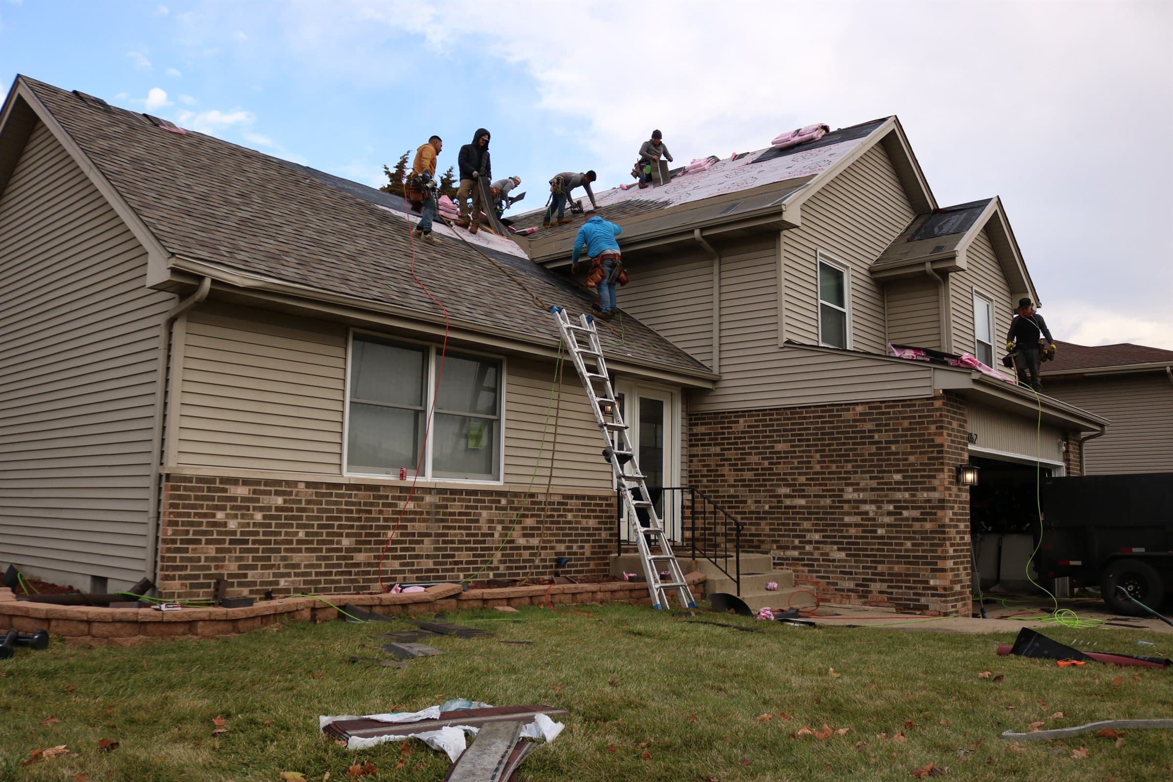 A Revere One crew installing shingles across the front elevation of a two-storey home