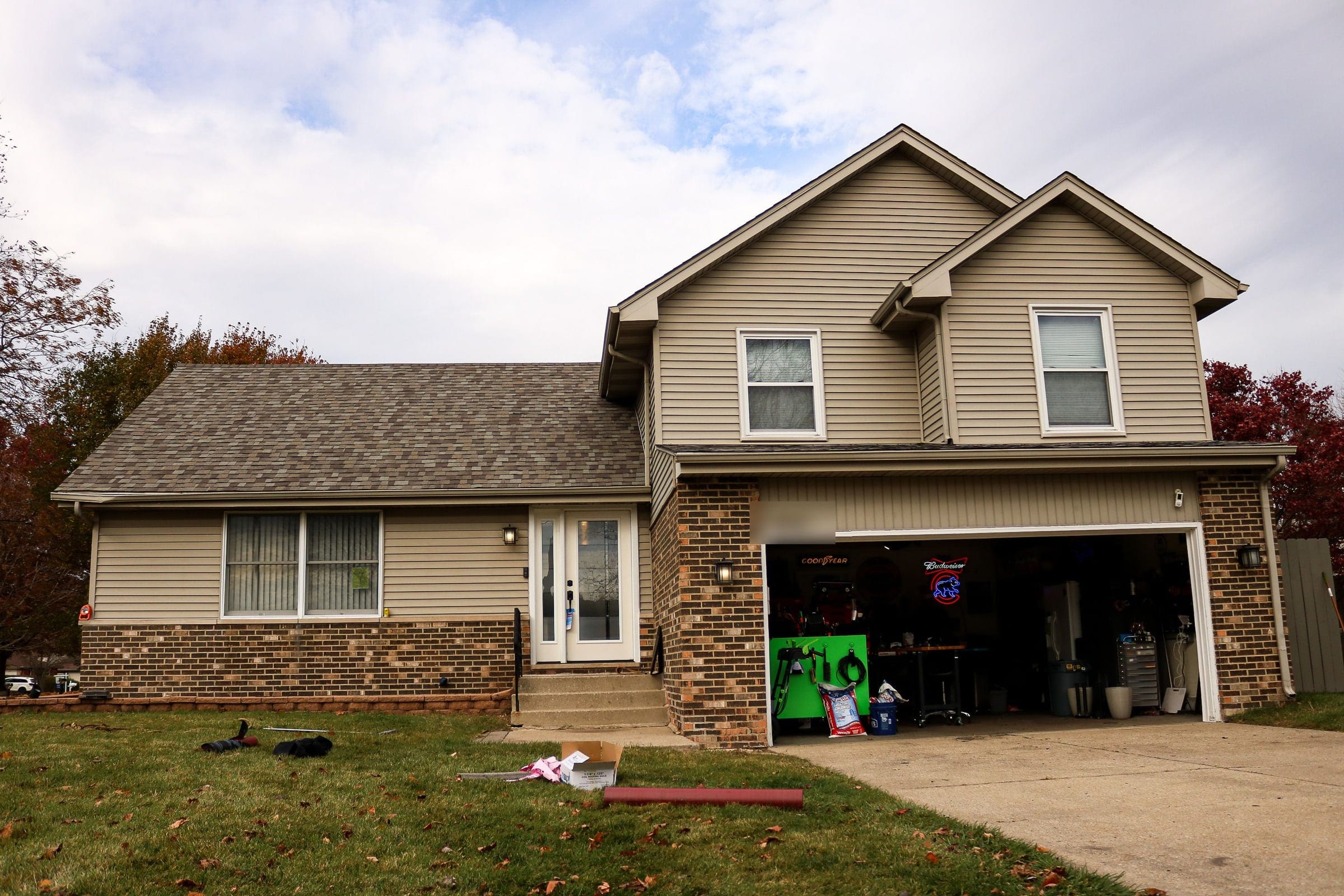 The finished replacement roof on a split-level home with brick and beige siding