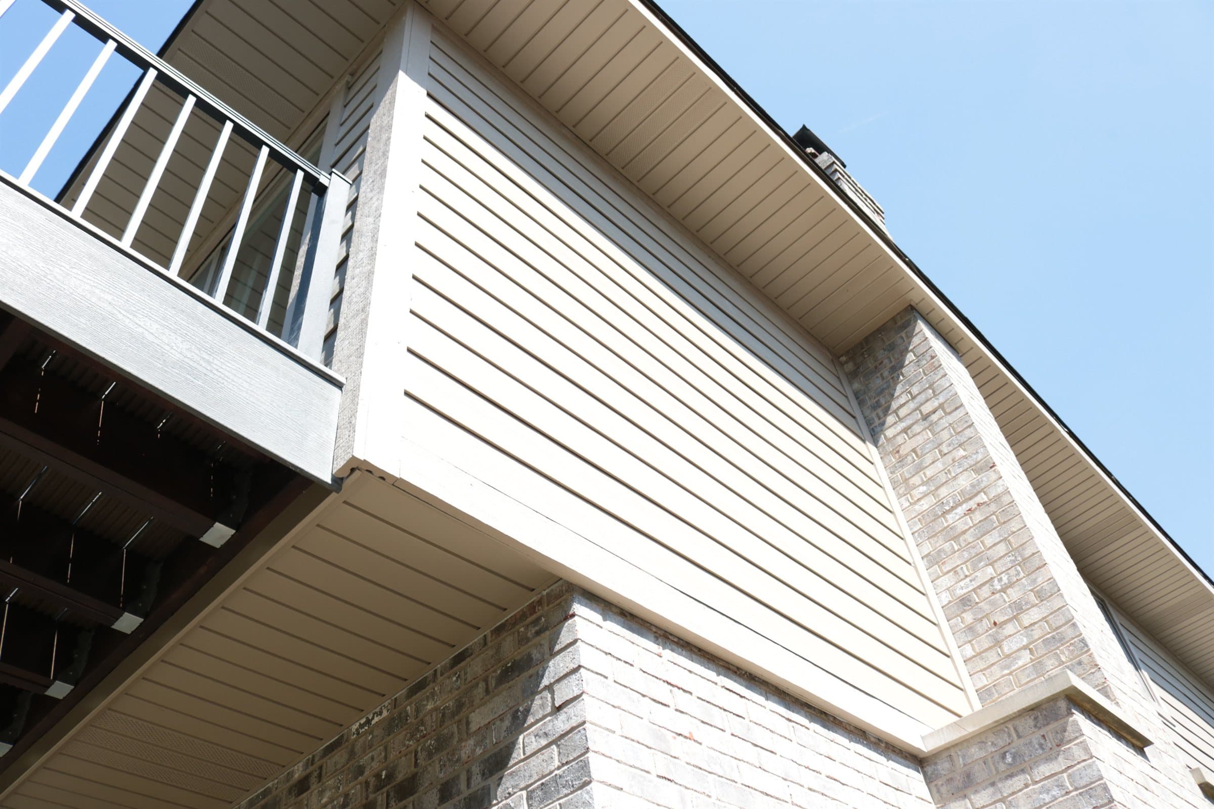 Close view of a finished gable end showing lap siding, soffit and fascia against a blue sky